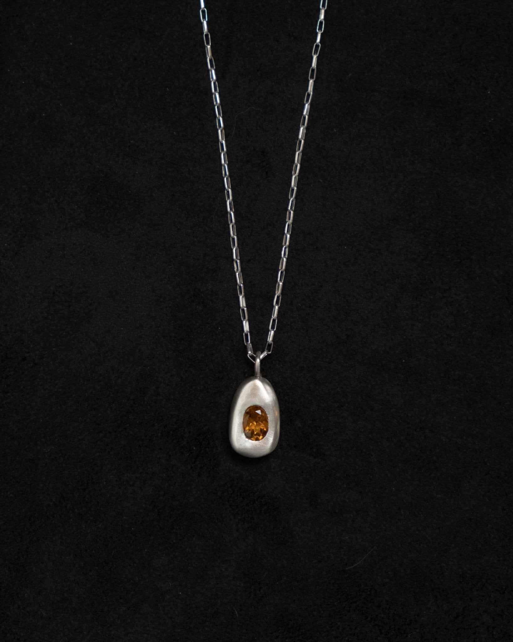 Minimalist silver egg pendant against clean background