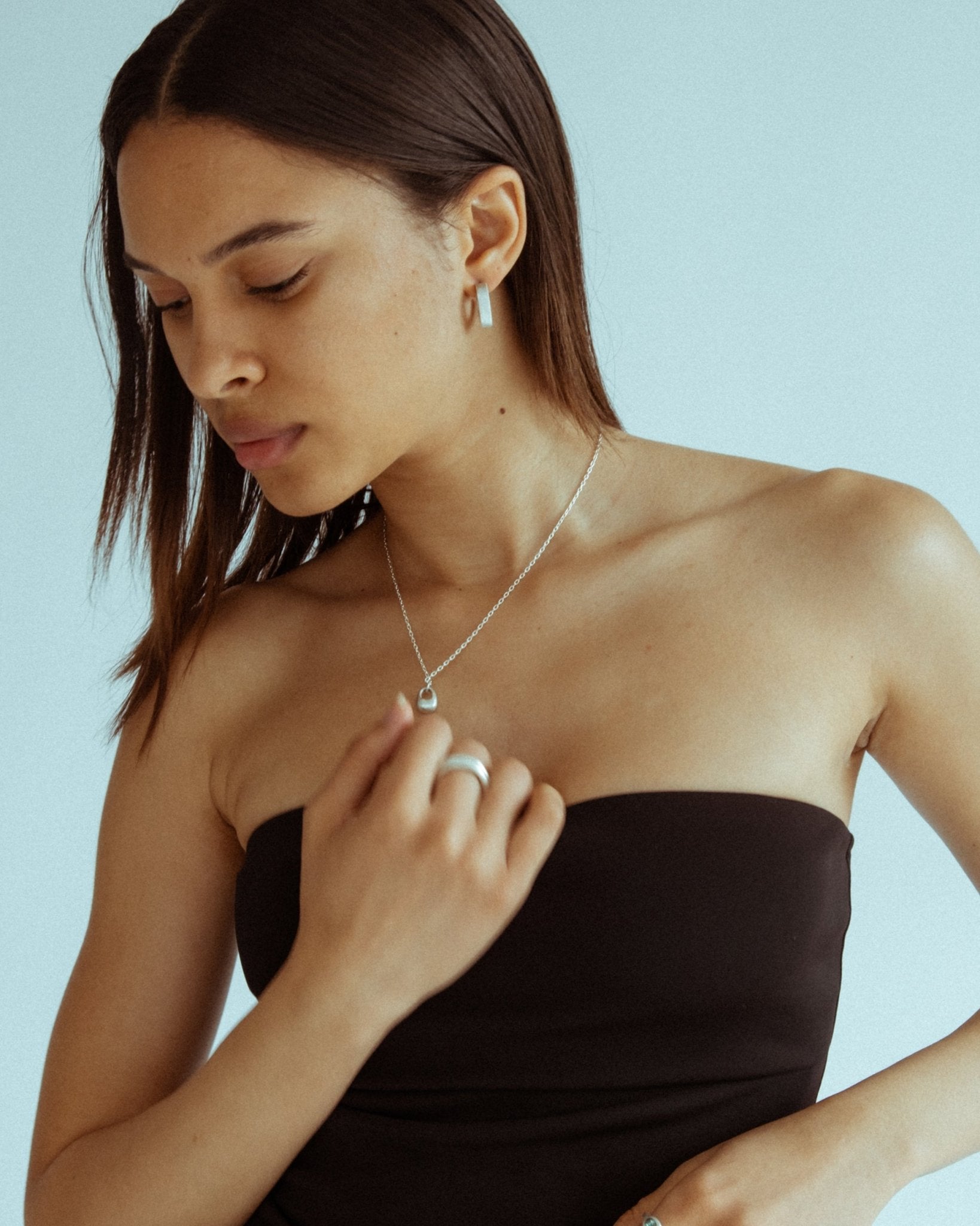 Small silver pendant necklace styled on model’s neck